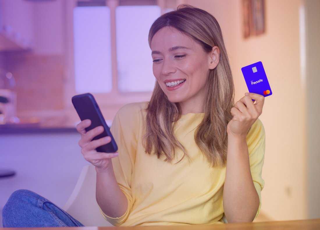 woman looking at a mobile phone and holding a Debit Mastercard in the other hand