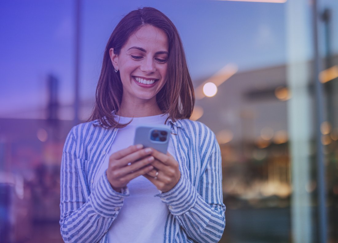woman smiling and looking at a mobile phone