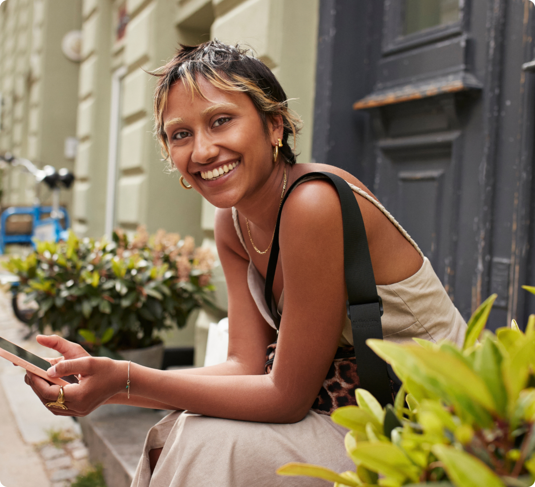 Person sitting on a porch smiling whilst using their smart phone