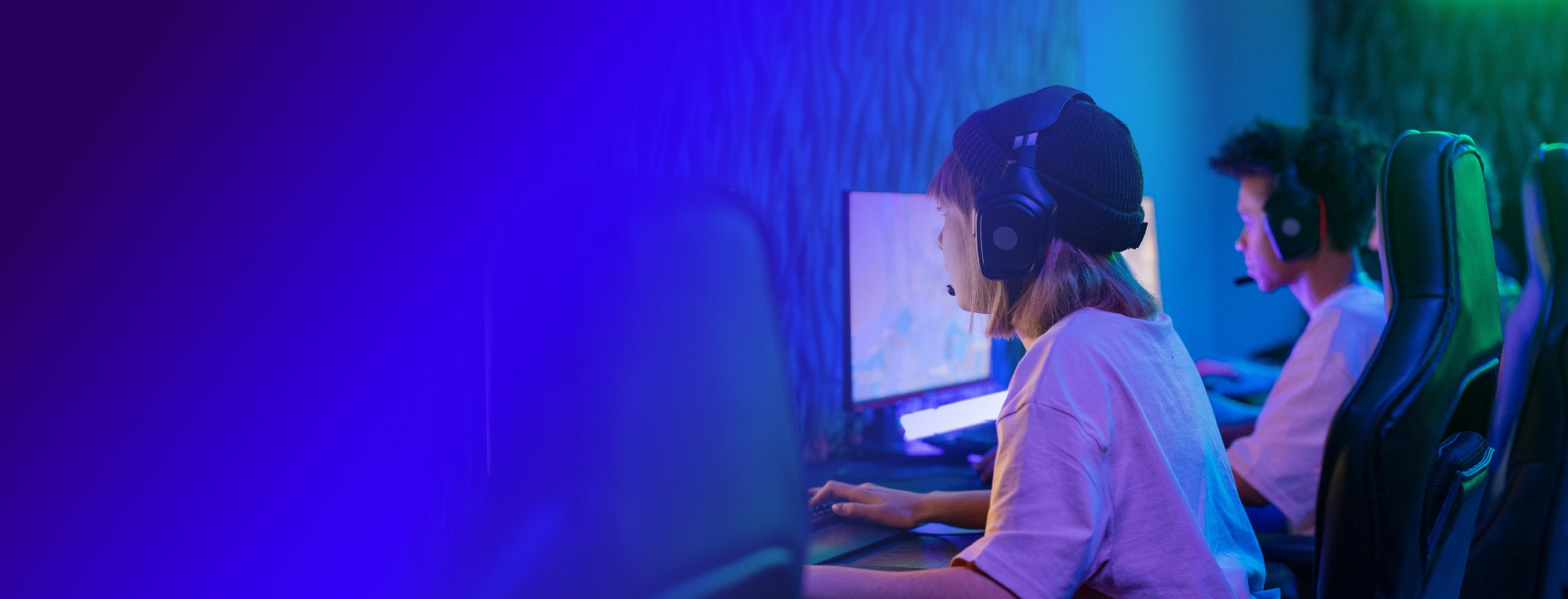 Two people with headphones are focused on their own PC