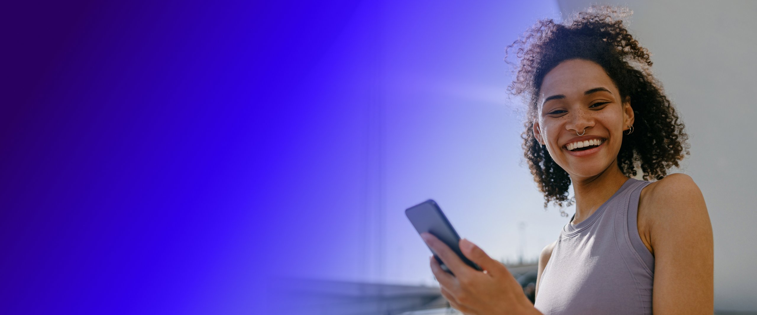 Woman holding a phone and looking at the camera and smiling brightly