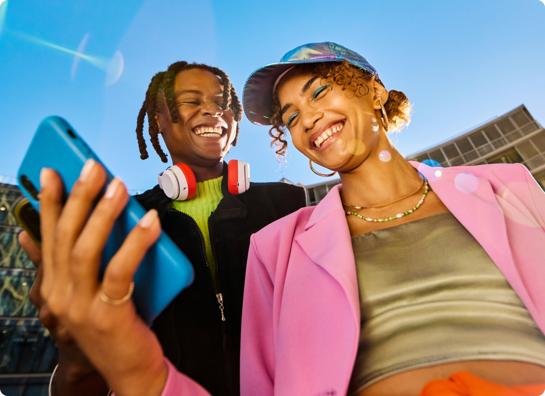 woman holding a phone and looking at it and a man laughing 