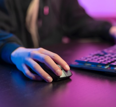 Person sitting at a table with a laptop and mouse in hand