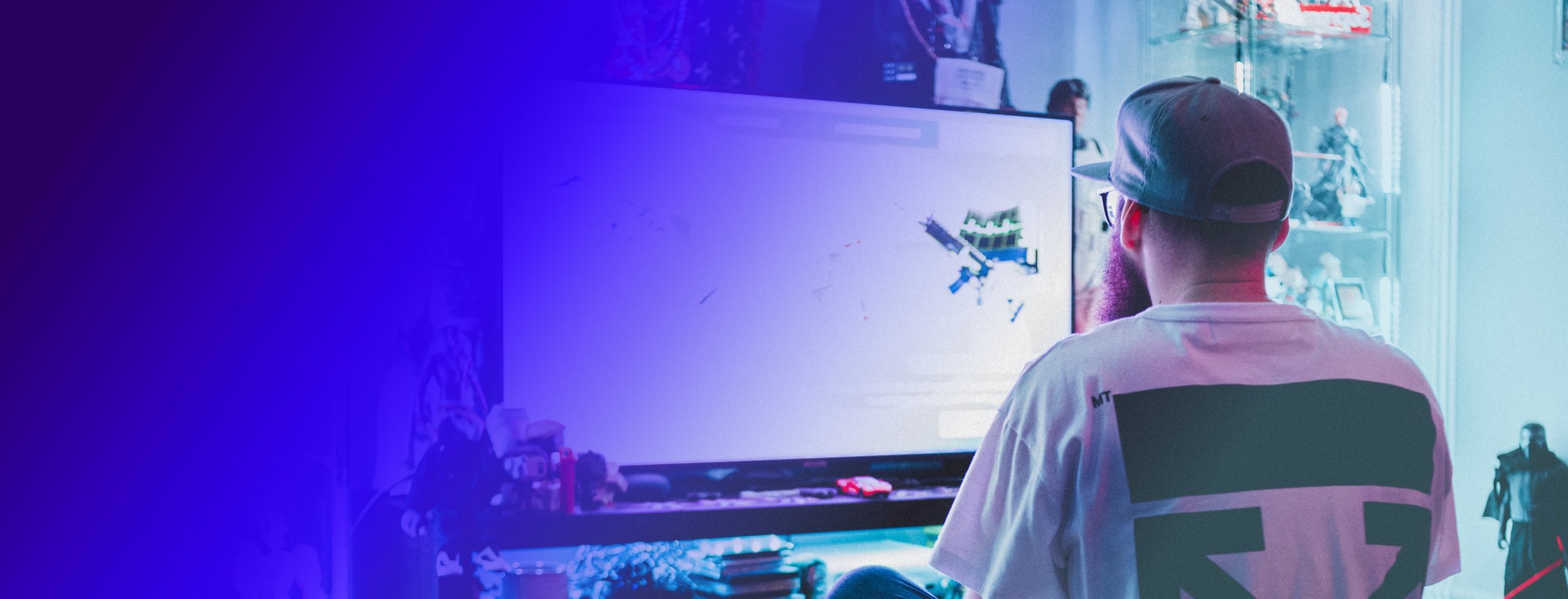 a man in a baseball hat playing a video game at his gaming computer